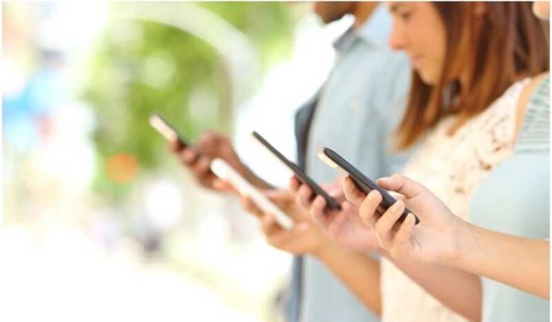 quatre personnes debout qui surfent sur son smartphone