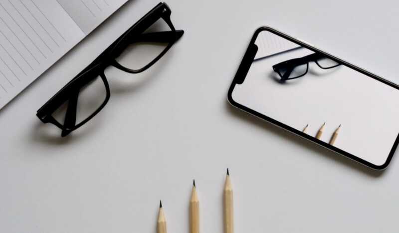 un telephone et des lunettes posés près d'un bloc notes