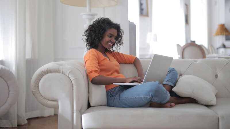 une femme devant son ordinateur sur le canapé