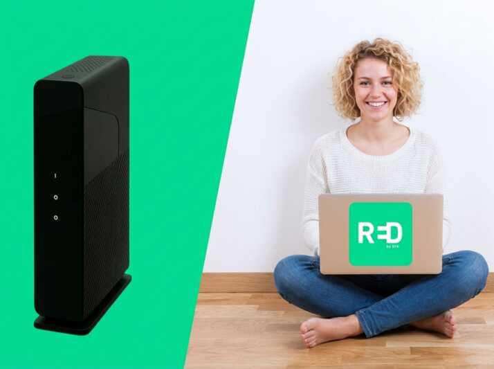 Une box internet noire à côté d'une femme assise au sol avec un ordinateur portable portant le logo RED by SFR.