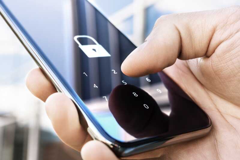 Un homme tape son code PIN pour déverrouiller son téléphone.
