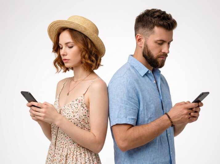 Un homme et une femme dos à dos utilisant chacun un smartphone sur fond blanc.
