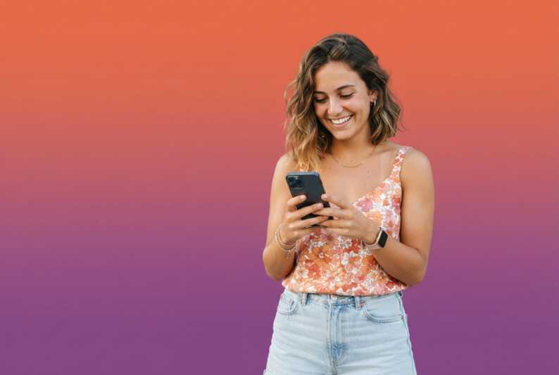 Jeune femme souriante consultant son smartphone sur un fond dégradé orange et violet.