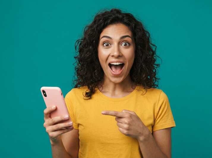 Femme aux cheveux blonds courts pointant un smartphone sur fond orange.