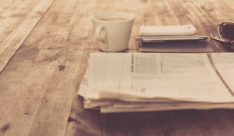 un Smartphone posé sur un bureau à coté d'un journal