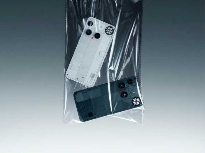 Deux smartphones Nothing Phone (2) blanc et gris dans un sachet plastique transparent sur fond gris dégradé.