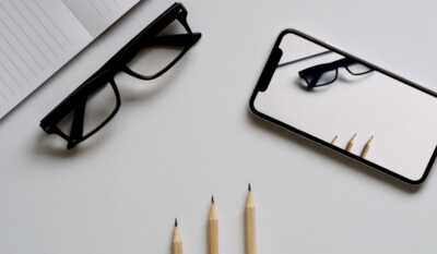 un telephone et des lunettes posés près d'un bloc notes