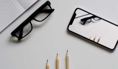 un smartphone, bloc note et une paire de lunette posé sur une table