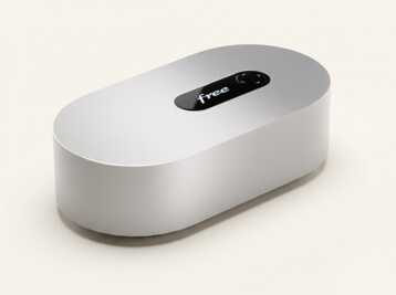 Box internet Free de forme ovale avec un écran tactile sur le dessus sur fond beige.