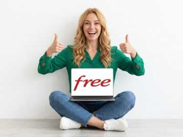 Femme blonde assise en tailleur tenant un ordinateur portable affichant le logo Free et faisant un signe pouce levé.