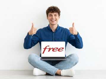 Une femme en pull vert assis en tailleur avec un ordinateur portable affichant le logo Free.