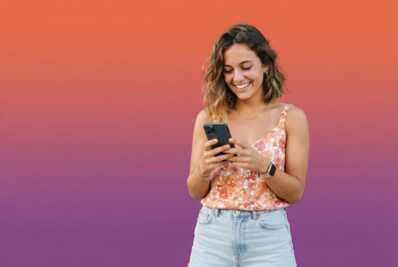 Jeune femme souriante consultant son smartphone sur un fond dégradé orange et violet.