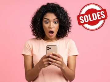 Femme surprise regardant son smartphone avec une vignette rouge Soldes en haut à droite sur fond rose.