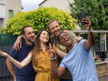 Quatre personnes prennent un selfie avec un smartphone Samsung Galaxy S23 en extérieur.