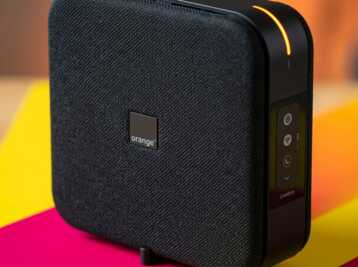 Vue rapprochée d'une box internet Orange Livebox noire avec voyant lumineux orange sur le côté.