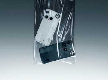 Deux smartphones Nothing Phone (2) blanc et gris dans un sachet plastique transparent sur fond gris dégradé.