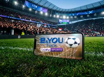 Smartphone posé sur la pelouse d'un stade de football affichant une publicité B&YOU et beIN SPORTS.