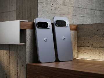 Deux smartphones Google Pixel posés sur une étagère en bois devant un mur en béton.