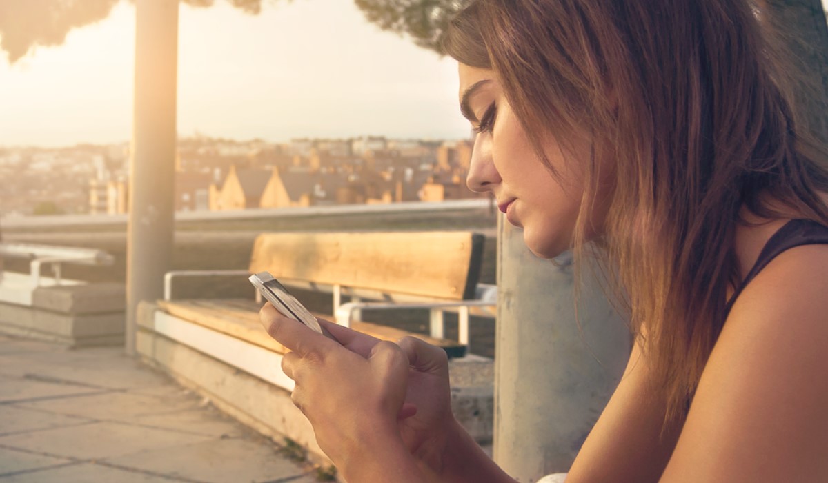 Jeune femme avec son smartphone sur un balcon