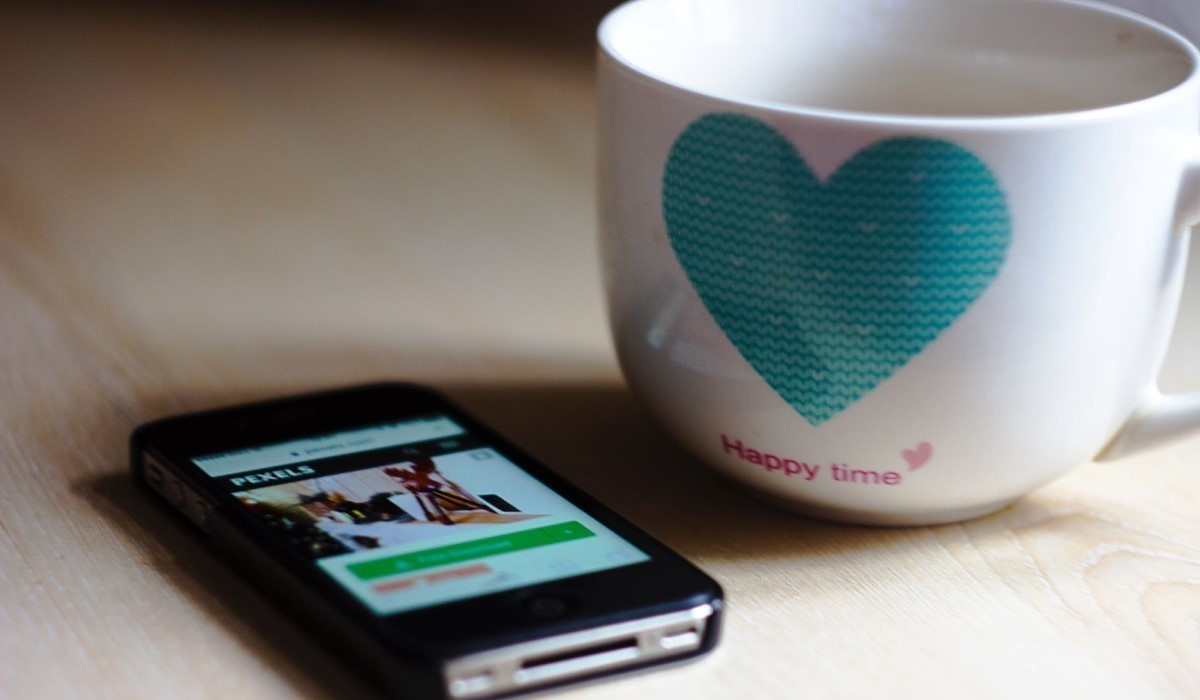 un smartphone et une tasse de thé posé sur une table