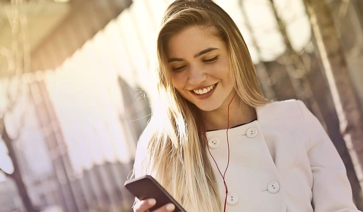 Jeune femme avec son smartphone sur un balcon