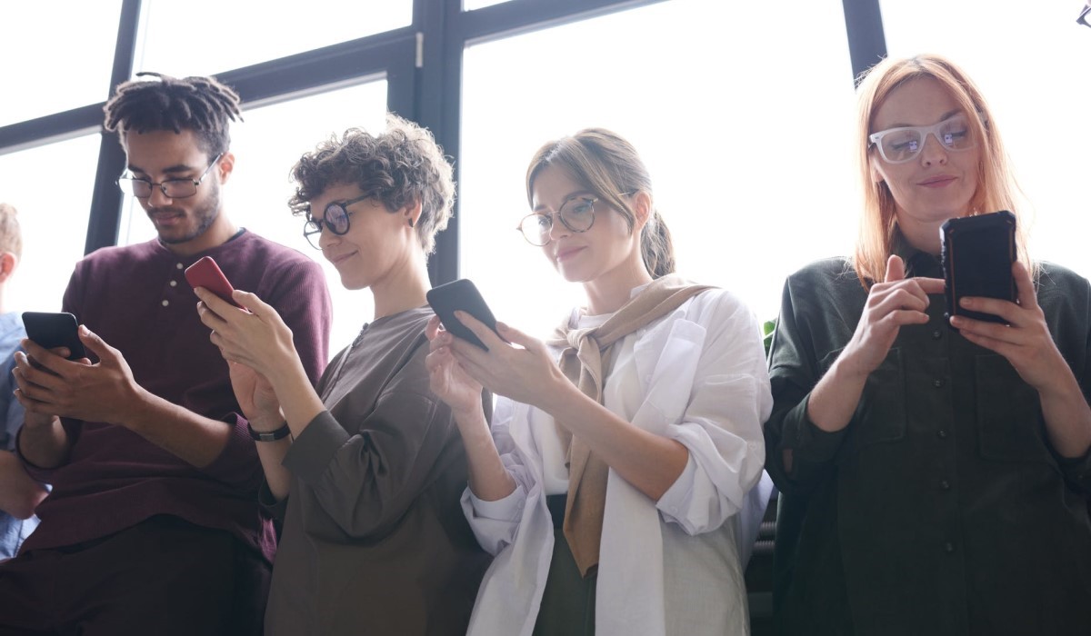 plusieurs personnes debout avec leur smartphone a la main