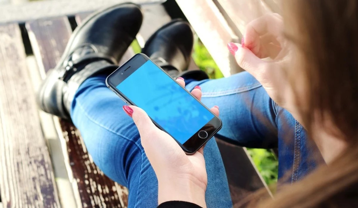 Femme sur un banc avec son iPhone dans les mains