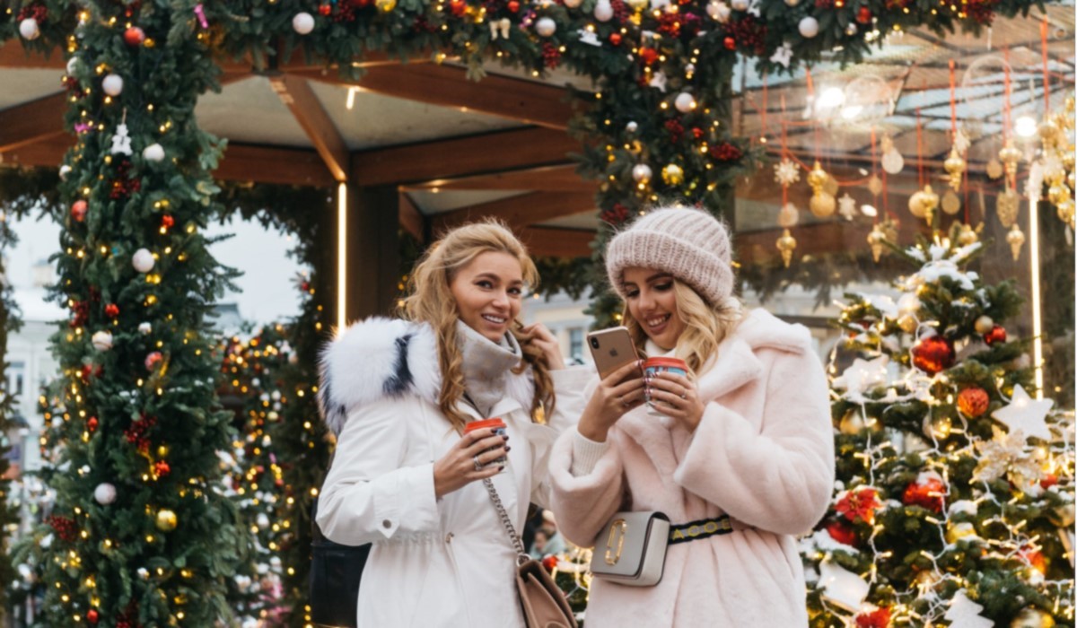 deux jeunes femmes au téléphone entourés par des décorations de noel