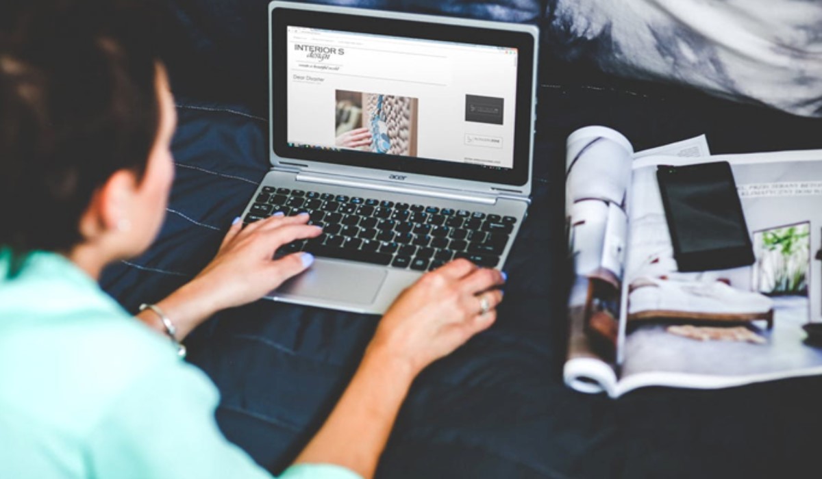 Femme devant son ordinateur avec son portable à côté
