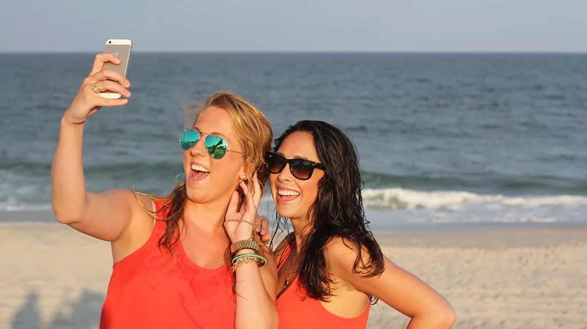 2 jeunes femmes qui se prennent en phot avec leur smartphone sur la plage