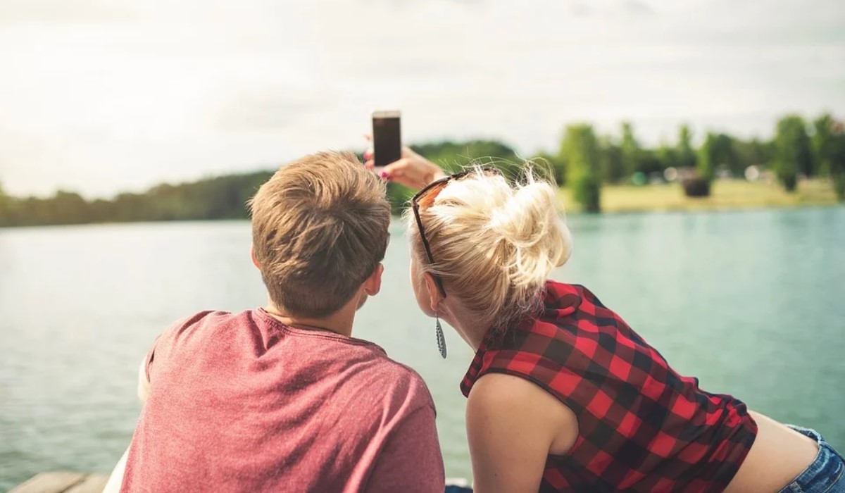 couple avec son smartphone devant un lac
