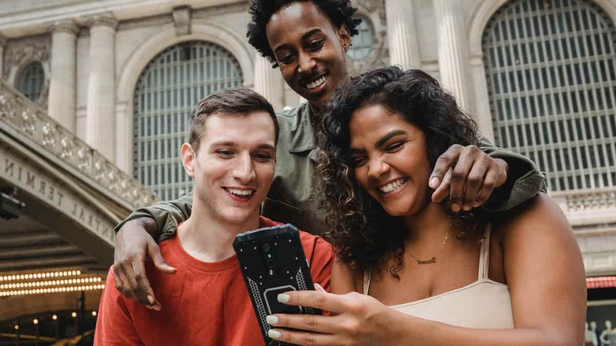 3 personnes souriantes devant un smartphone