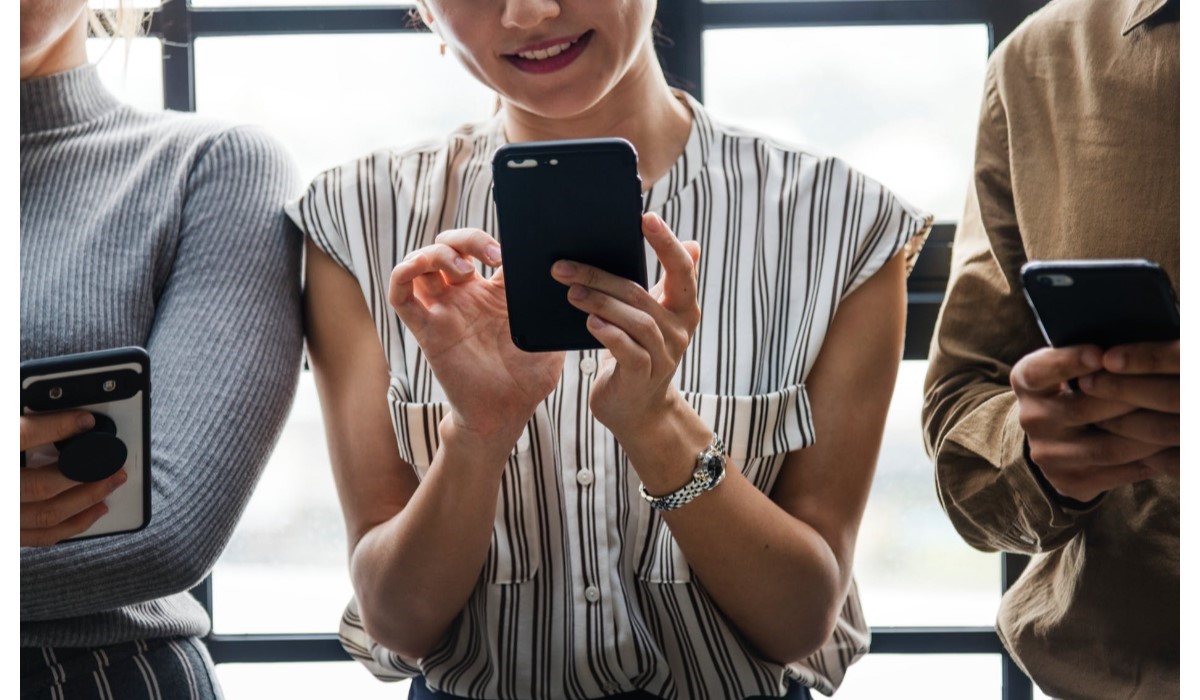 trois personnes debout avec leur smartphone en main