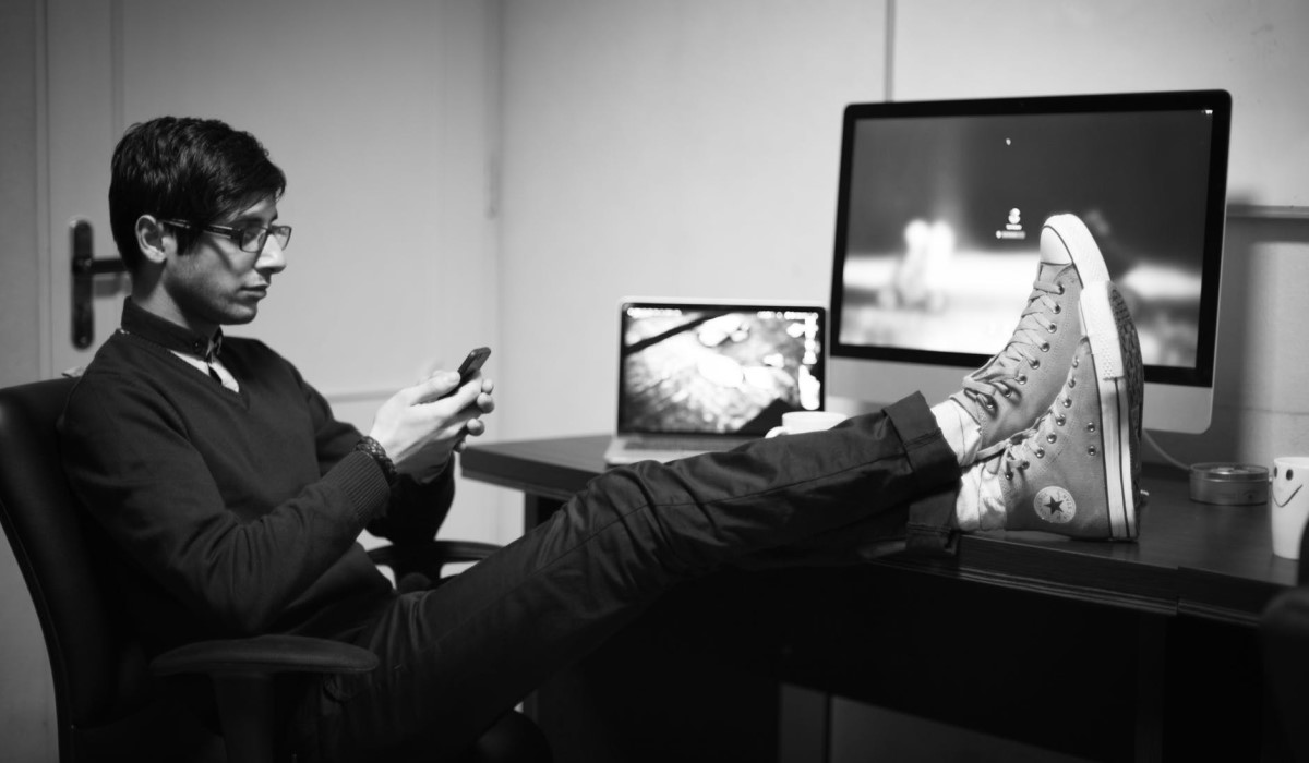 jeune homme assis à son bureau avec son smartphone a la main