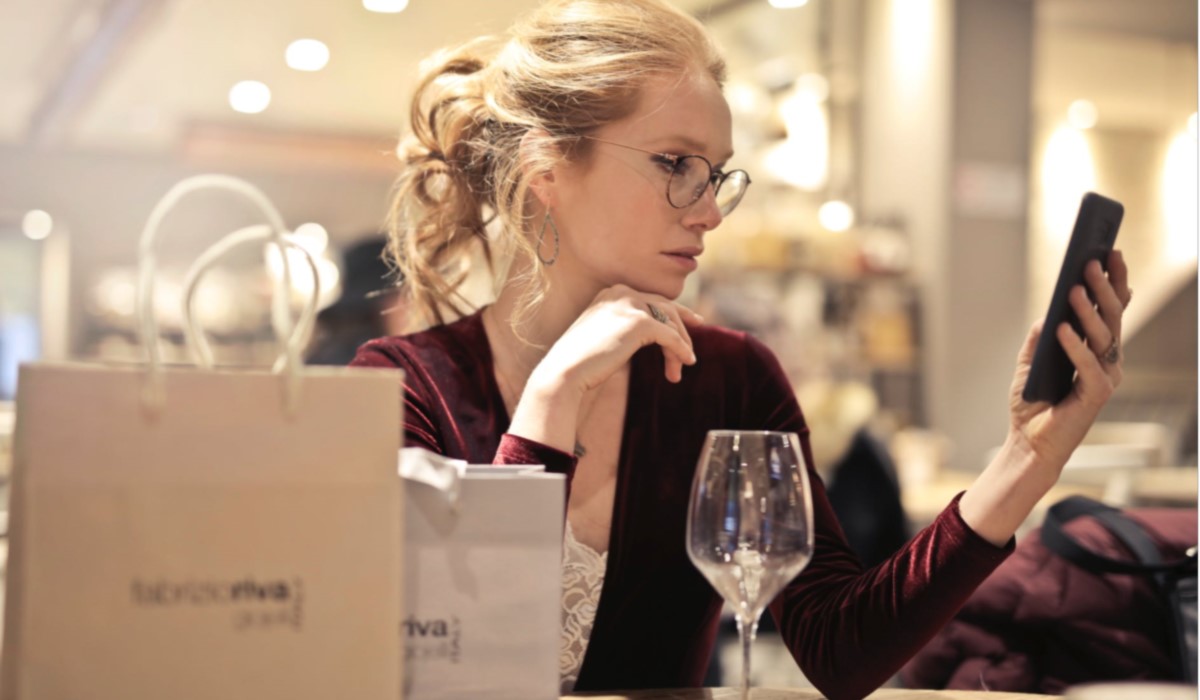 une jeune femme au restaurant avec son smartphone et sac de shopping