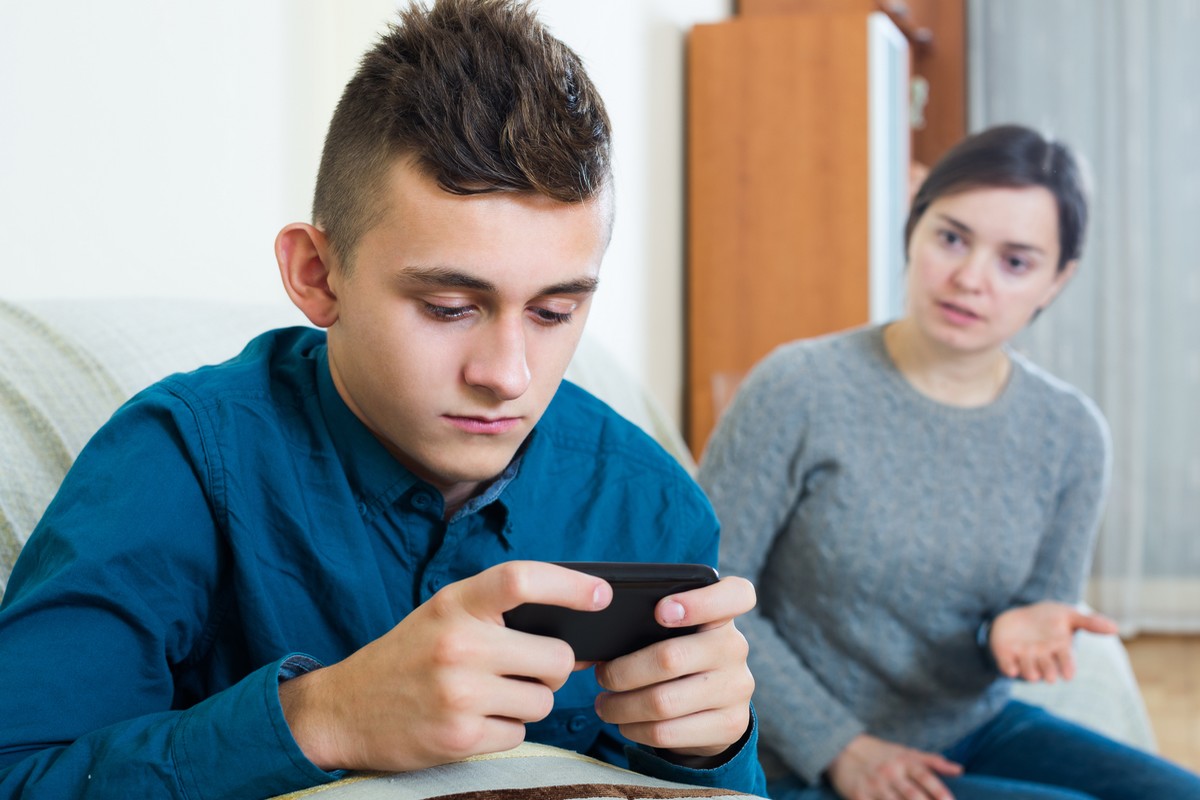 Un adolescent est scotché sur son smartphone et n'écoute pas sa mère