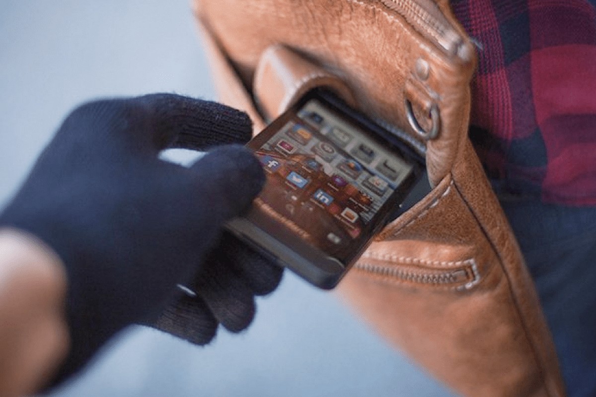 Un homme vole un smartphone dans le sac à main d'une femme